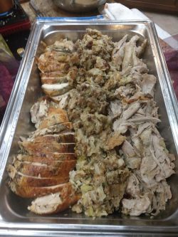 A tray with sliced roast turkey, stuffing in the center, and shredded turkey meat on the right.
