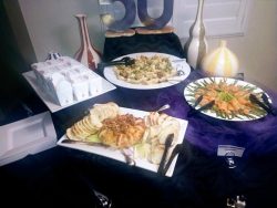 A buffet table with assorted appetizers, crackers, cheese, salads, and decorative vases arranged for an event.