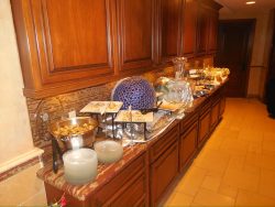 A buffet setup on a kitchen counter with various covered dishes, plates, and serving utensils arranged neatly.